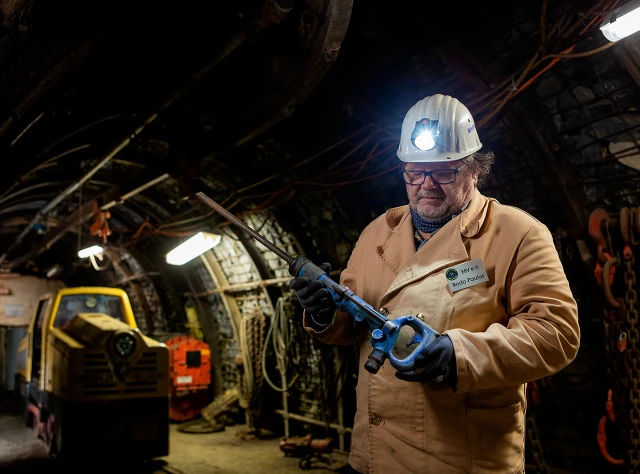Ein Bergmann im Stollen neben einer Lok